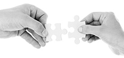 Photo of two puzzle pieces being joined together, symbolizing partnership